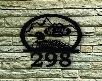 Può includere: Cartello per numeri civici in metallo nero con una silhouette di loon, una catena montuosa e un cartello "WELCOME". Il numero civico è 298.