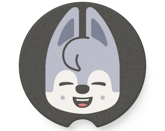 Könnte beinhalten: Ein runder, schwarzer Auto-Untersetzer mit einem lächelnden Cartoon-Wolfsgesicht. Der Wolf hat hellblaues Fell, eine schwarze Nase und einen roten, offenen Mund. Der Untersetzer hat unten eine kleine Kerbe.