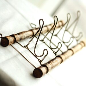 May include: A decorative display stand with a wire frame and wooden dowels. The stand has a series of curved wire supports and is designed to hold plates or other items. The wooden dowels have a dark brown finish.