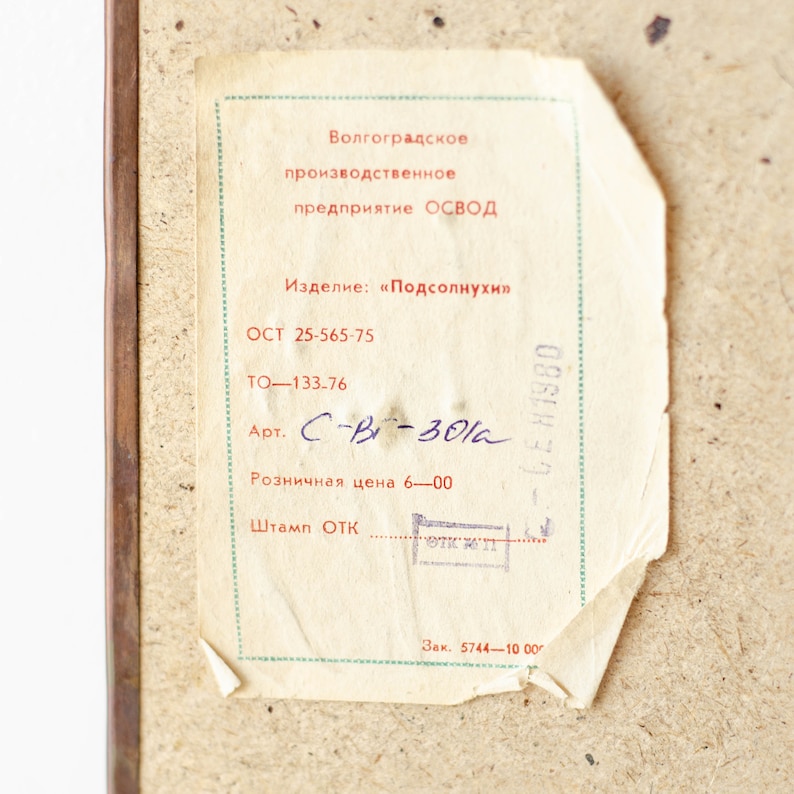 May include: A white label with black text that reads "Volgograd Production Enterprise OSVOD". The label also includes the text "Product: "Sunflowers"", "OST 25-565-75", "TO-133-76", "Art. C-B-301a", "Retail price 6-00", "Stamp ОТК", and "Order 5744-1000g".
