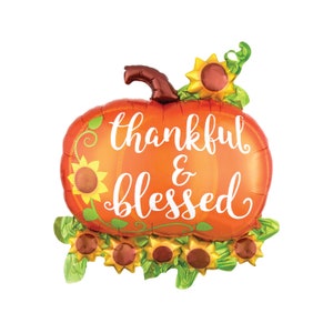 May include: Orange and green foil pumpkin balloon with the text "thankful & blessed" in white. The balloon is decorated with sunflowers.