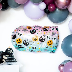 May include: A large, silver, Halloween-themed balloon with a pink and blue ombre effect. The balloon is decorated with a variety of Halloween icons, including pumpkins, ghosts, bats, and cats.