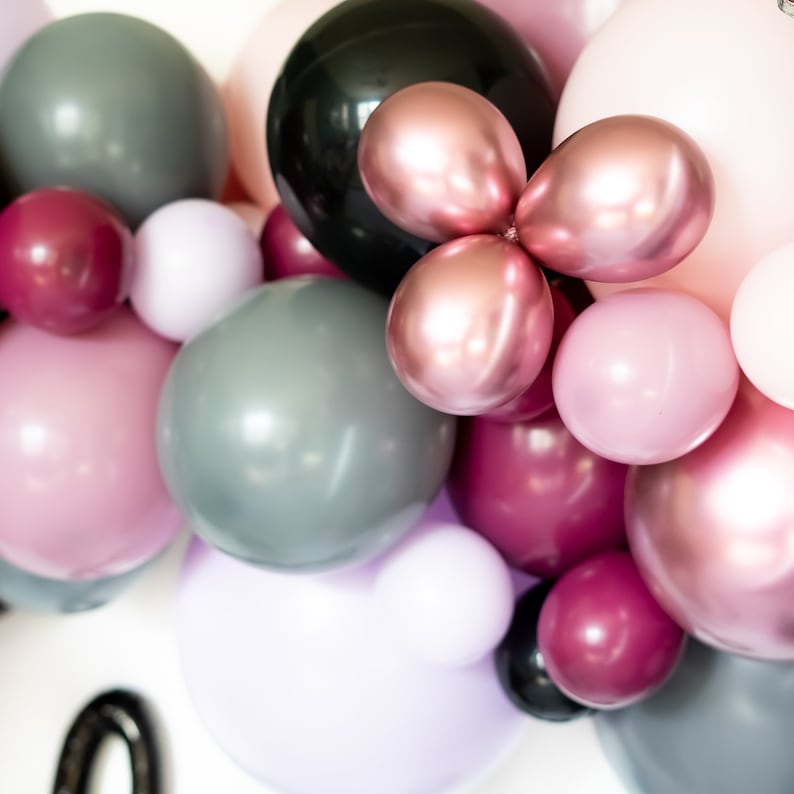 May include: A collection of balloons in various shades of pink, gray, and black. The balloons are arranged in a cluster, creating a festive and celebratory atmosphere.