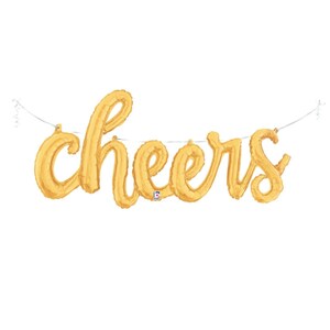 May include: Gold foil balloon banner spelling "cheers" hanging from a white string.