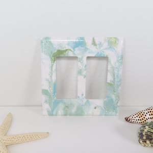 Cubierta de interruptor de luz doble con diseño abstracto pintado: espirales de color verde azulado y menta