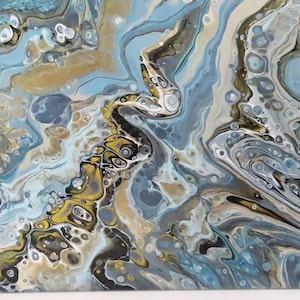May include: Abstract acrylic pour painting with a fluid design. The artwork features a mix of colors, including shades of blue, gold, and white, creating a marbled effect. The painting has a glossy finish and a unique, organic pattern.