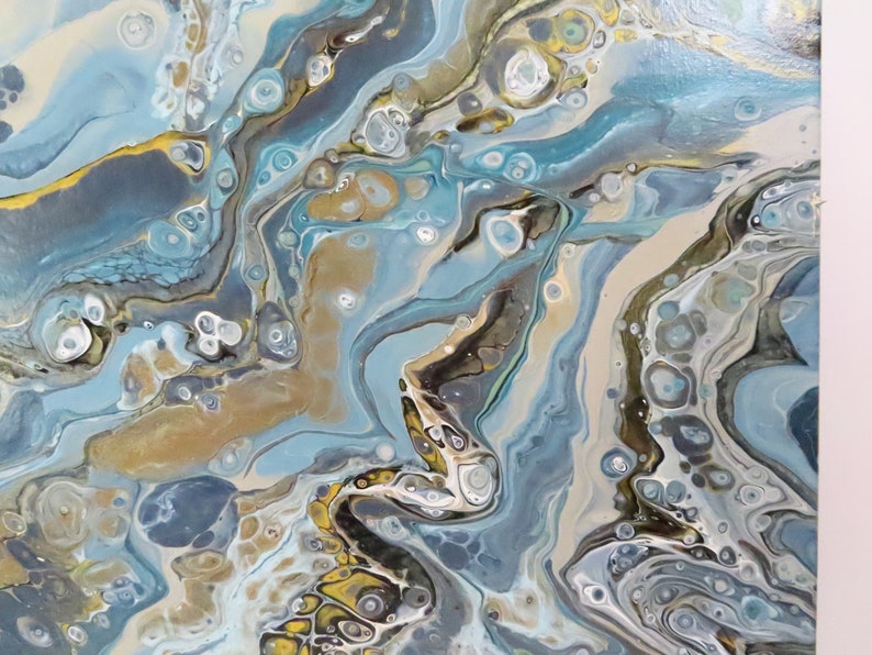 May include: Abstract acrylic painting with fluid art technique. The artwork features a blend of light blue, gold, and neutral tones, creating a marbled effect. The composition includes swirling patterns and organic shapes, evoking a sense of movement and depth.