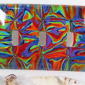 May include: A colorful light switch cover with a swirling pattern of red, blue, green, and yellow. The cover has four switch openings.