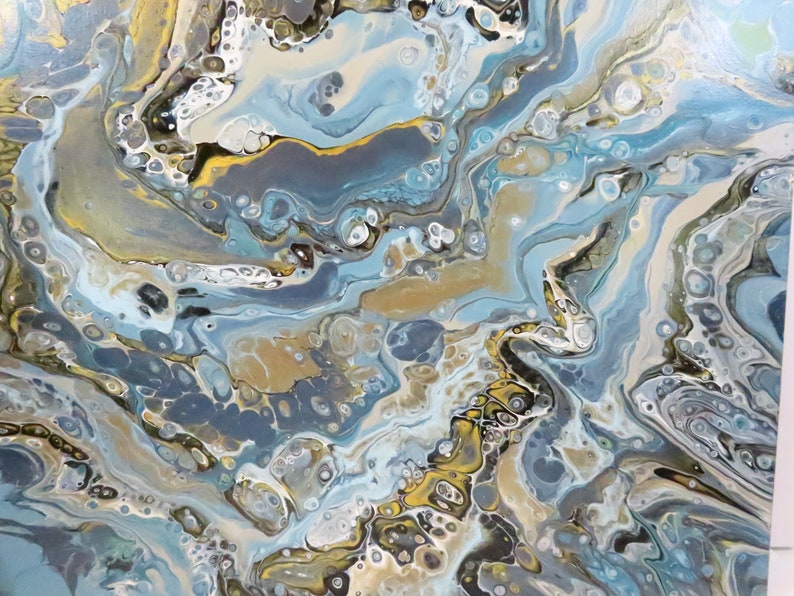 May include: Abstract acrylic pour painting with flowing patterns in shades of blue, gold, gray, and white. The artwork features a marbled effect with organic shapes and textures, creating a dynamic and fluid composition.