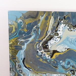 May include: Abstract acrylic painting on canvas with a fluid design. The artwork features a blend of blue, gray, white, and gold hues, creating a marbled effect. The colors swirl and mix, forming organic shapes and patterns. The canvas is square.