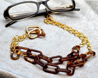 Corrente grossa para óculos em padrão tartaruga. Suporte para óculos em acrílico marrom e dourado.