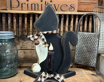 May include: Black wooden cat candle holder with a black and white checkered ribbon and a black candle. The cat is standing on a black wooden star.