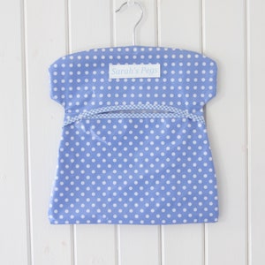 May include: A blue and white polka dot fabric hanging organizer with a white label that says "Sarah's Pegs".