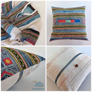 Op de afbeelding: Een verzameling handgemaakte textielartikelen, waaronder een shirt en kussens. Het shirt is crèmekleurig met blauwe, rode en zwarte strepen. De kussens hebben een denimachtige stof met kleurrijke strepen en geometrische patronen.