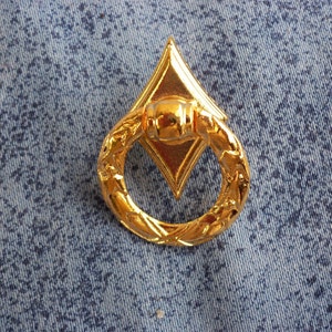 Peut inclure: Une poignée de tirage en métal doré avec un centre en forme de diamant et un motif floral décoratif.