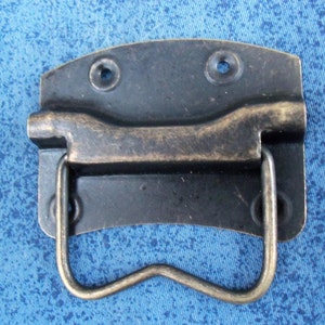 Peut inclure: Une poignée en métal noir avec une finition en laiton et un design incurvé ouvert. La poignée a deux petits trous en haut et deux en bas.