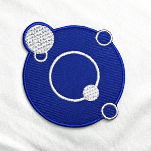 Könnte beinhalten: Blauer gestickter Aufnäher mit einem weißen Kreis und drei kleineren weißen Kreisen darin. Der Aufnäher hat einen weißen Umriss.