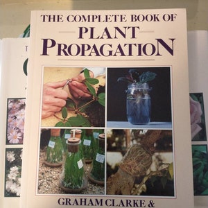 May include: A book titled "The Complete Book of Plant Propagation" by Graham Clarke & Alan Toogood. The cover features images of plant propagation techniques, including cuttings, water propagation, and layering. The book is on a light-colored surface.