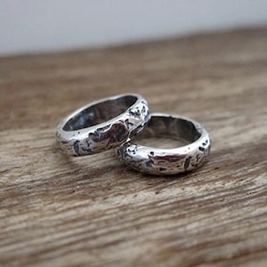May include: Two silver rings with a textured, hammered finish. The rings are stacked on top of each other.