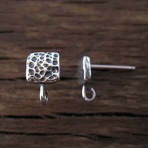 May include: A pair of silver earring findings with a textured square shape and a loop on the bottom.