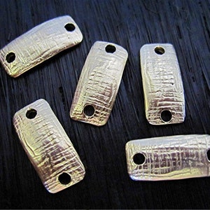 May include: Five silver-toned metal connector charms with a textured surface and two holes each. The charms are rectangular and slightly curved.
