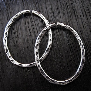 May include: Two silver hoop earrings with a hammered texture.