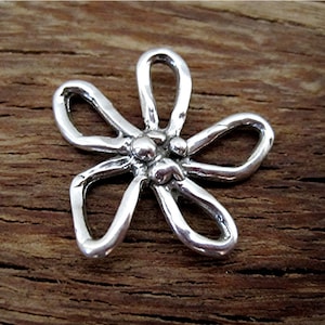 May include: A silver-colored, five-petal flower pendant with a hammered texture. The center features three small, round accents. The pendant is displayed against a rustic, wooden background, highlighting its handcrafted appearance.