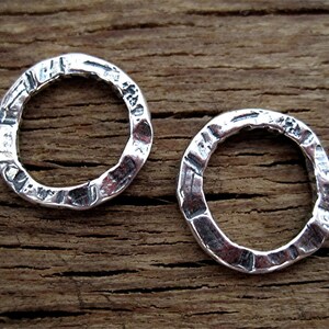 Puede incluir: Dos anillos de plata con un acabado texturizado martillado. Los anillos son redondos y tienen un borde interior liso.