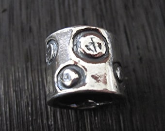 May include: Silver ring with a textured surface and a pattern of small circles.