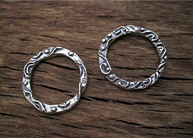 May include: Two silver rings with a textured, wavy design. The rings are made of sterling silver and have a hammered finish.