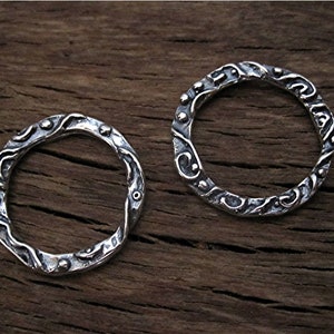 May include: Two silver rings with a textured, wavy design. The rings are made of sterling silver and have a hammered finish.