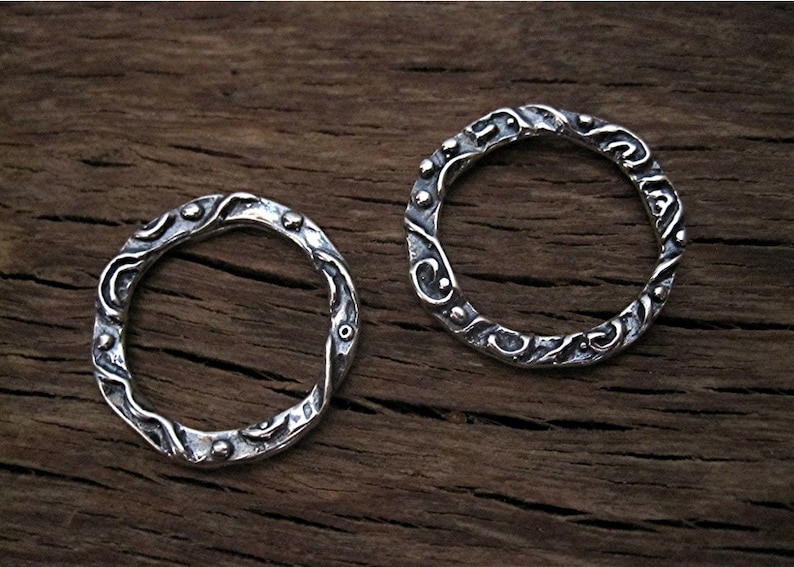 May include: Two silver rings with a textured, wavy design. The rings are made of sterling silver and have a hammered finish.