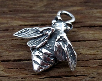 May include: A silver charm in the shape of a bee with detailed wings and a textured body. The charm has a loop at the top for attaching to a bracelet or necklace.
