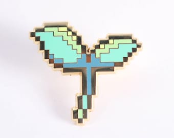 Puede incluir: Un pin dorado con forma de brote de planta pixelado. El brote presenta hojas de color azul claro y verde con un tallo azul. El diseño tiene una estética retro de videojuego de 8 bits, perfecto para añadir un toque único a cualquier atuendo.