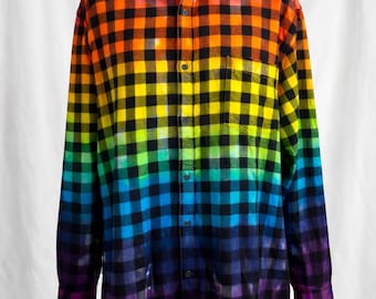 May include: Rainbow plaid button-down shirt on a mannequin. The long-sleeved shirt features a vibrant gradient of colors, transitioning from red to purple. The shirt has a classic collar and a single chest pocket.