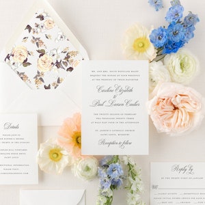 May include: Wedding invitation suite with white envelopes, a floral patterned inner envelope, and a white card with the text "Caroline Elizabeth to Paul Larsen Caulier" and the date "The Twenty-Second of February Two Thousand Twenty-Three at Half Past Four in the Afternoon" and the location "St. Joseph's Catholic Church Saint Louis, Missouri". The card also includes the text "Reception to follow".