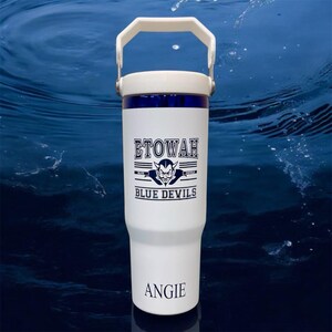 May include: White insulated tumbler with a white handle and lid, featuring the text "ETOWAH BLUE DEVILS" and a devil graphic in navy blue. The name "ANGIE" is printed at the bottom. The tumbler has a navy blue band near the top.