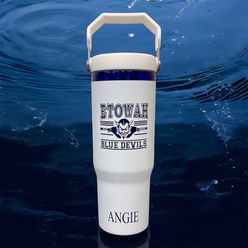 May include: White insulated tumbler with a white handle and lid, featuring the text "ETOWAH BLUE DEVILS" and a devil graphic in navy blue. The name "ANGIE" is printed at the bottom. The tumbler has a navy blue band near the top.