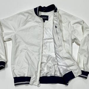 May include: White Lands' End bomber jacket with navy blue trim on the collar, cuffs, and hem. The jacket has a full zipper closure and two front pockets. The interior lining is white and has a mesh panel.