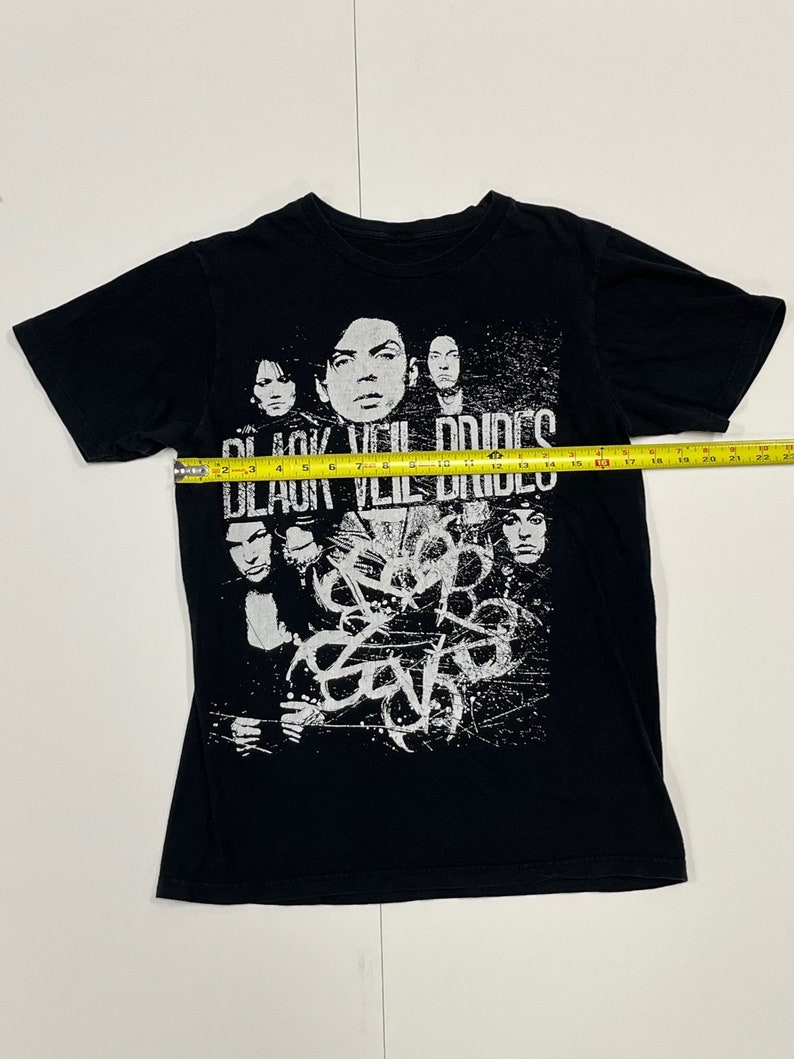 May include: Black t-shirt featuring a band graphic. The shirt displays the band name "Black Veil Brides" in white text above a collage of band members. The band's logo is also visible in white. The shirt is approximately 22 inches wide.