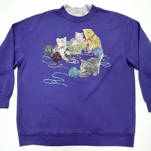 May include: Purple sweatshirt with an embroidered design of four kittens playing with yarn balls.