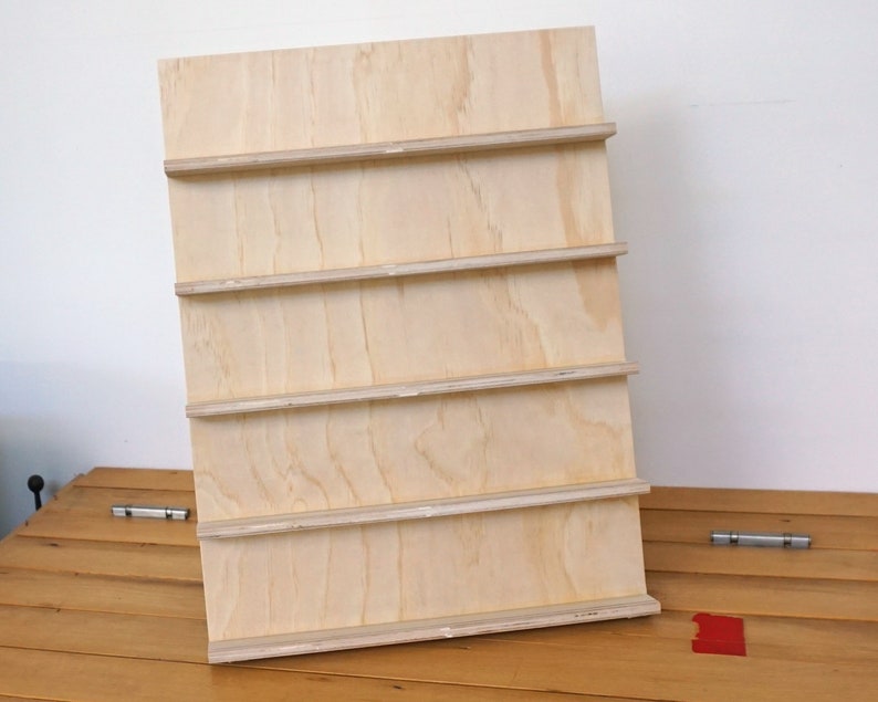May include: A wooden shelf unit with five shelves. The shelves are made of plywood and are unfinished.