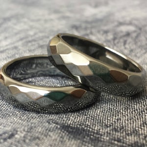 May include: Two silver rings with a faceted, geometric design. The rings are stacked on top of each other.