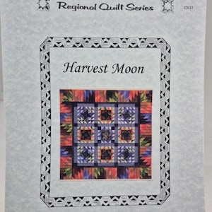 May include: A printed pattern for a quilt titled "Harvest Moon" from the Regional Quilt Series. The quilt design features a central square with nine smaller squares, each with a star pattern. The border is a mix of colors including orange, blue, and purple.