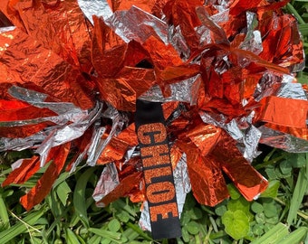 May include: Orange and silver cheerleading pom pom with a black strap that says "CHLOE" in orange glitter letters.