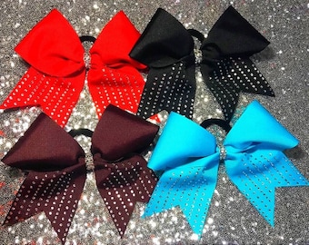 May include: Four cheer bows with rhinestones. The bows are red, black, maroon, and turquoise.