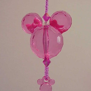 May include: Pink crystal charm with a Mickey Mouse head design and a key charm. The Mickey Mouse head has a small pink bow on the left ear.