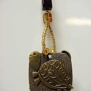 May include: A gold-toned turtle charm with a detailed design hangs from a beaded chain with amber and black beads.