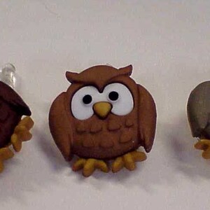 May include: Three brown owl buttons with white eyes and beaks. The owls are in different shades of brown and have a textured surface.