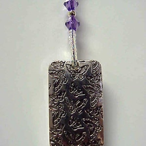 May include: A silver charm with a rectangular shape and a design of multiple butterflies. The charm is attached to a silver chain with purple crystal beads.